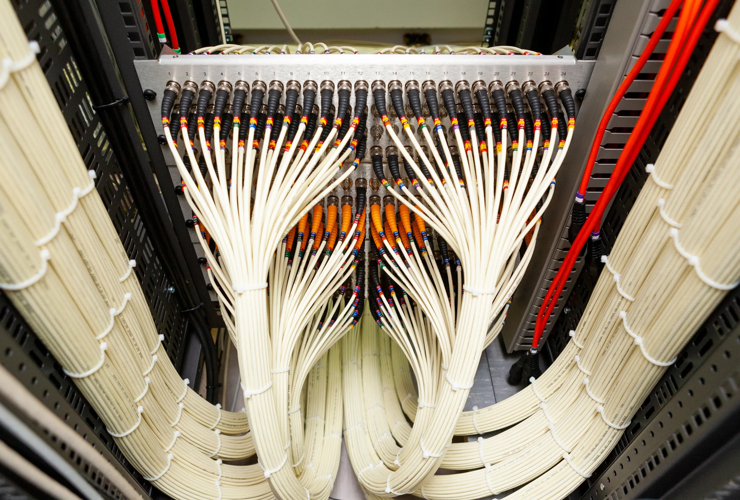 Organized fiber optic cables fanning into a rack patch panel.